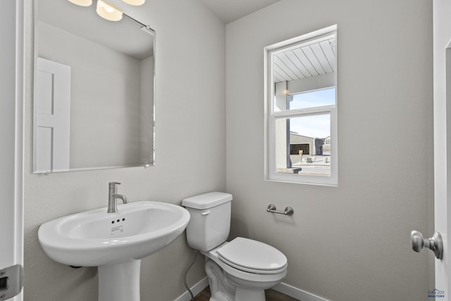 bathroom featuring toilet, baseboards, and a sink