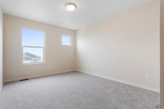 unfurnished room featuring carpet flooring, visible vents, and baseboards