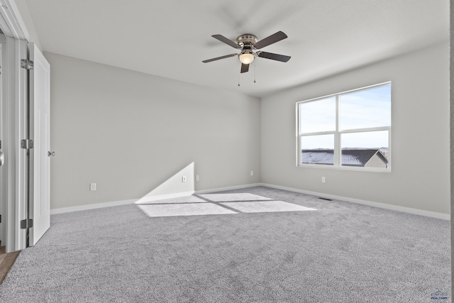 carpeted empty room with a ceiling fan and baseboards