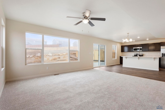 unfurnished living room featuring baseboards, dark colored carpet, a wealth of natural light, and recessed lighting