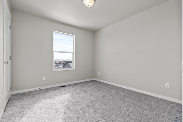 carpeted spare room featuring visible vents and baseboards