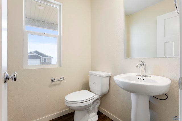 bathroom with toilet, baseboards, and wood finished floors