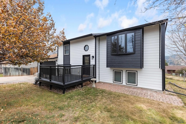 back of house with a deck and a lawn