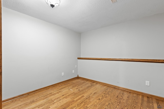 spare room featuring light wood-type flooring and a textured ceiling