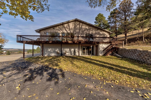 back of house with a garage, a wooden deck, and a yard