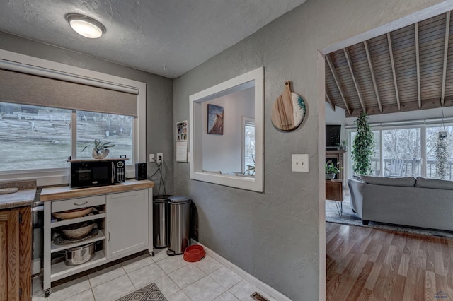 interior space with a textured ceiling, light hardwood / wood-style flooring, and vaulted ceiling