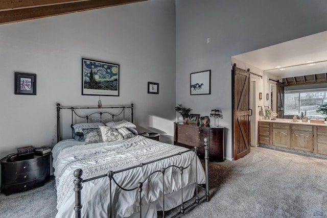 carpeted bedroom featuring connected bathroom, high vaulted ceiling, and a barn door