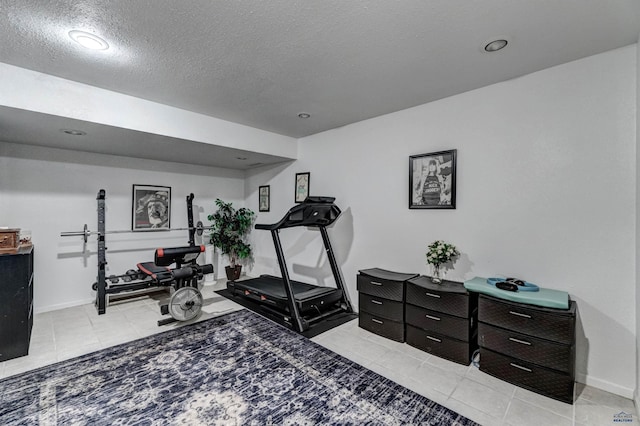 exercise area with light tile patterned floors and a textured ceiling