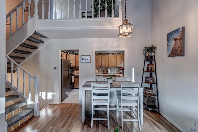 dining space featuring a chandelier, a high ceiling, and light wood-type flooring