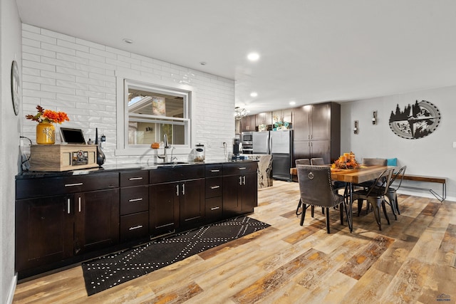 kitchen featuring dark brown cabinetry, sink, light wood-type flooring, and appliances with stainless steel finishes