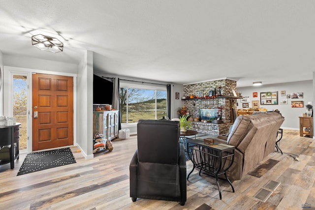 living room featuring a fireplace, light wood-type flooring, and a textured ceiling