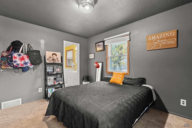 carpeted bedroom featuring ensuite bath and a textured ceiling