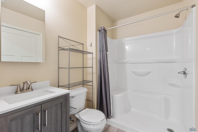 bathroom featuring hardwood / wood-style floors, a shower with curtain, toilet, and vanity