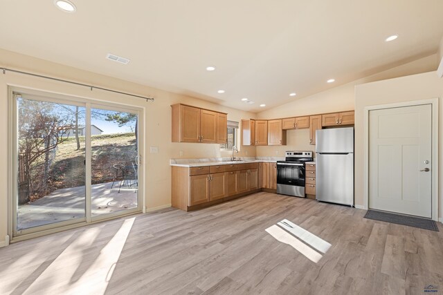 kitchen featuring stainless steel appliances, vaulted ceiling, light hardwood / wood-style floors, and sink