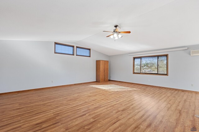 empty room with ceiling fan, vaulted ceiling, and light hardwood / wood-style flooring