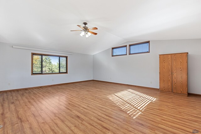 spare room with light wood-type flooring, vaulted ceiling, and ceiling fan