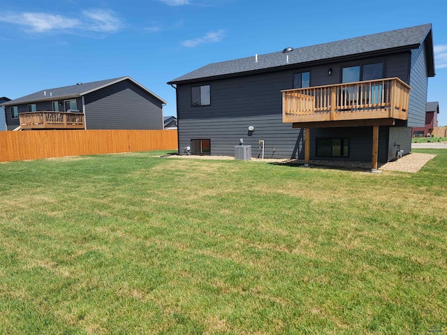 rear view of property with central air condition unit, a wooden deck, and a lawn