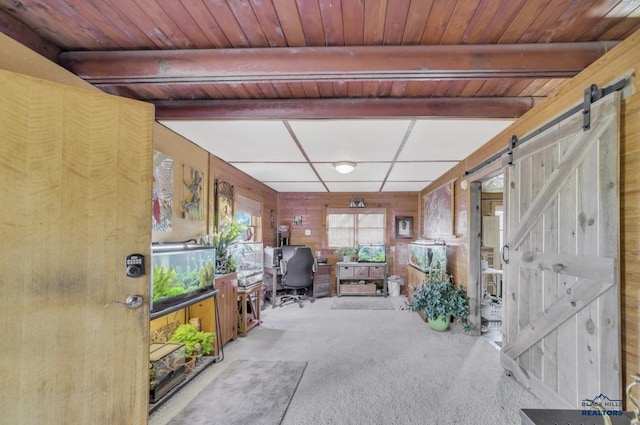 unfurnished office featuring beam ceiling, a barn door, wooden ceiling, and wooden walls