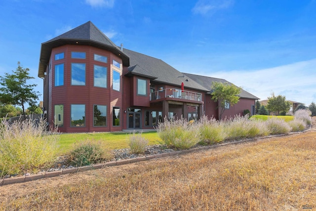 rear view of property with a yard and a balcony