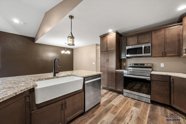 kitchen featuring sink, pendant lighting, wood-type flooring, lofted ceiling, and appliances with stainless steel finishes