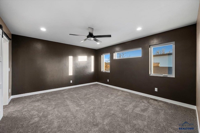 unfurnished room with carpet flooring, ceiling fan, and a barn door