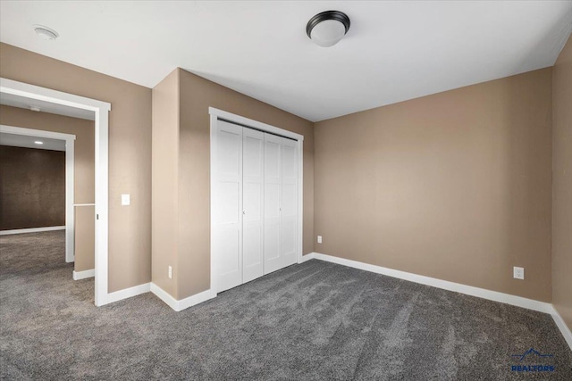 unfurnished bedroom featuring dark carpet and a closet