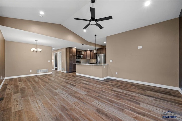 unfurnished living room featuring sink, ceiling fan with notable chandelier, dark wood-type flooring, and lofted ceiling