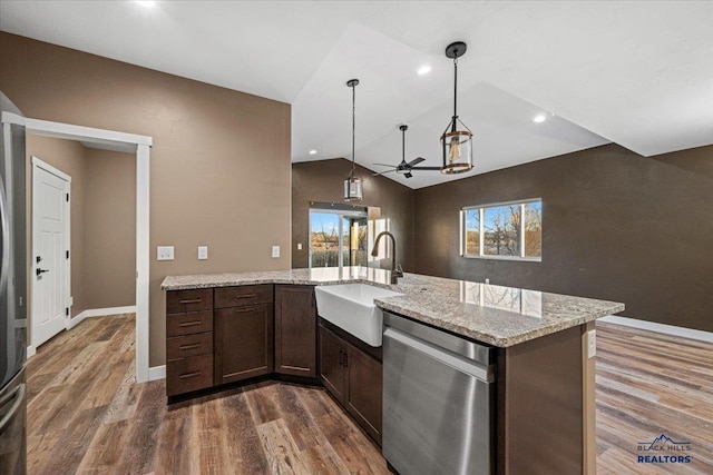 kitchen featuring light stone countertops, vaulted ceiling, dark wood-type flooring, sink, and dishwasher