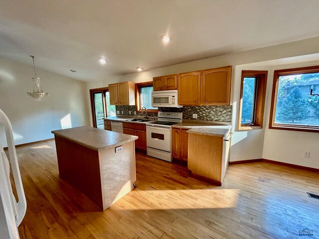 kitchen with light wood-type flooring, white appliances, decorative light fixtures, and a kitchen island