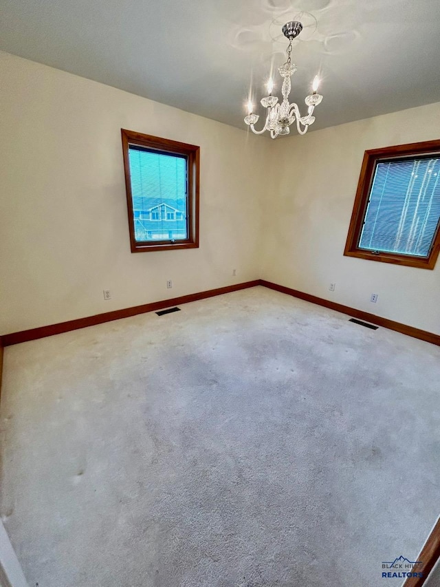 empty room featuring carpet and an inviting chandelier