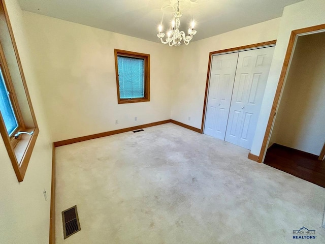 unfurnished bedroom with a notable chandelier, light colored carpet, and a closet