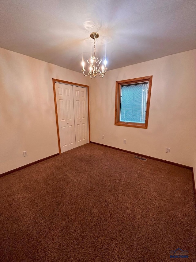 spare room with carpet and an inviting chandelier