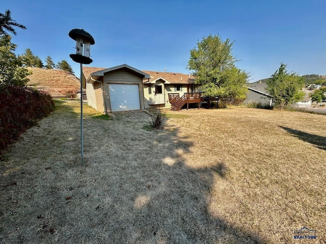 view of front of property featuring a garage, a front lawn, and a wooden deck