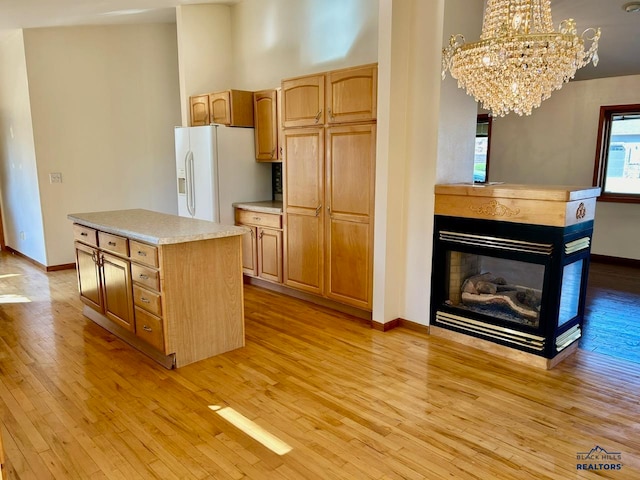 kitchen with a chandelier, a kitchen island, light wood-type flooring, and white refrigerator with ice dispenser