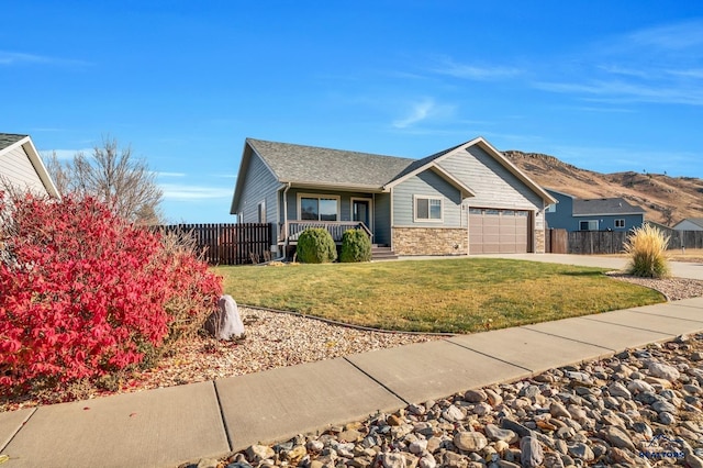 view of front of house featuring a front yard, a porch, a garage, and a mountain view