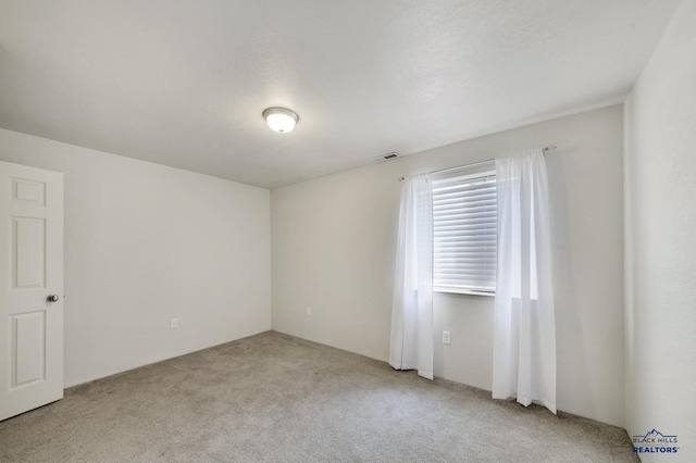 unfurnished room featuring a textured ceiling and light carpet