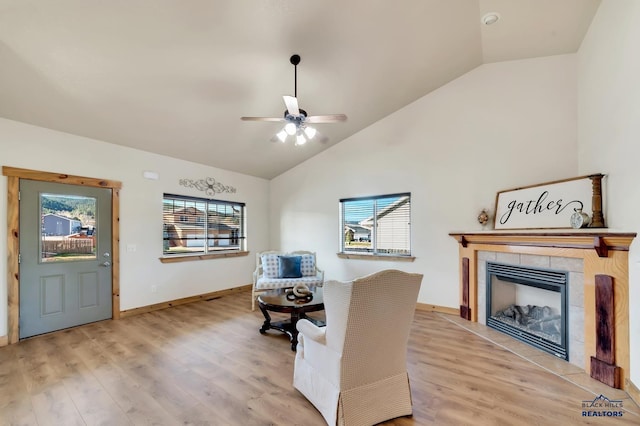 living area with ceiling fan, light wood-type flooring, lofted ceiling, and a wealth of natural light