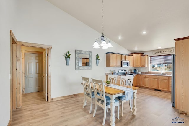 dining space featuring an inviting chandelier, high vaulted ceiling, light hardwood / wood-style flooring, and sink