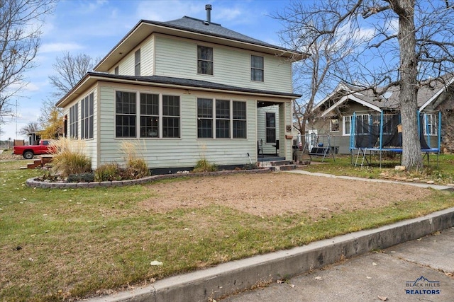 view of front of house with a trampoline and a front lawn