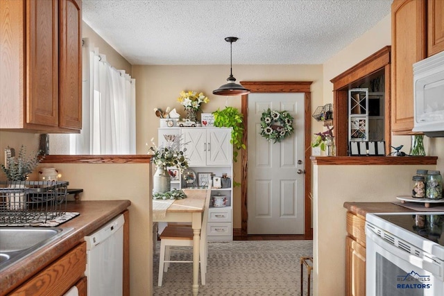 kitchen with a textured ceiling, white appliances, and hanging light fixtures