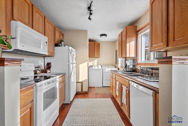 kitchen with white appliances, sink, light hardwood / wood-style flooring, washing machine and dryer, and a textured ceiling