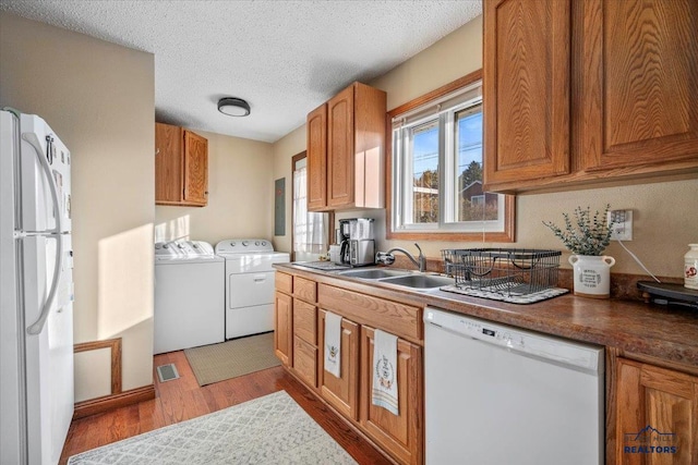 kitchen featuring sink, independent washer and dryer, a textured ceiling, white appliances, and light wood-type flooring