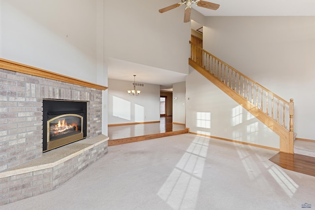 unfurnished living room featuring carpet, a brick fireplace, ceiling fan with notable chandelier, and high vaulted ceiling