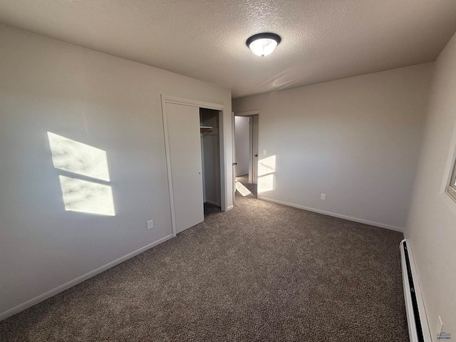 unfurnished bedroom featuring dark carpet, a textured ceiling, a closet, and a baseboard radiator