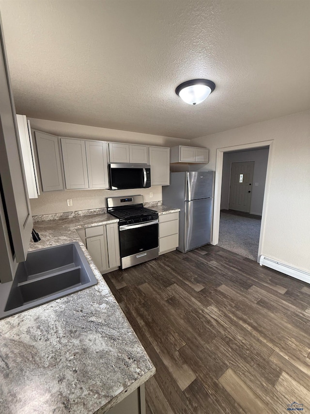 kitchen with light stone countertops, sink, stainless steel appliances, dark hardwood / wood-style flooring, and a textured ceiling