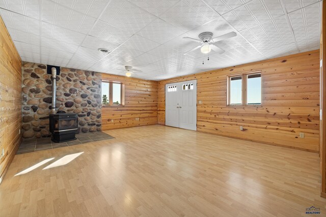 unfurnished living room with hardwood / wood-style floors, a wood stove, and ceiling fan