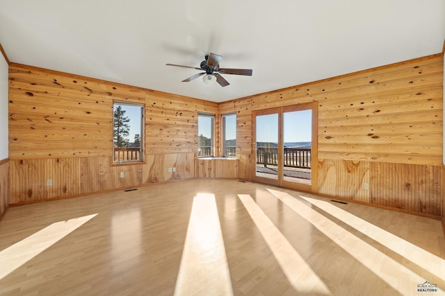 spare room with wood walls, ceiling fan, and light hardwood / wood-style floors