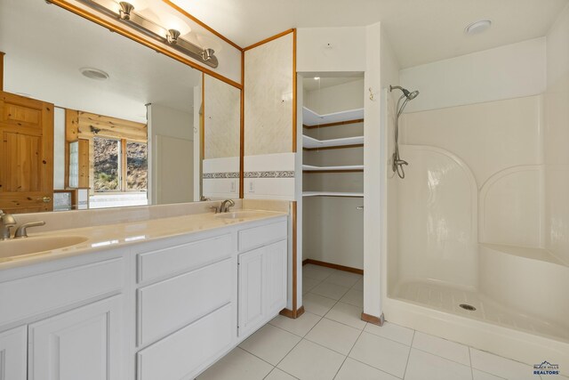 bathroom with tile patterned flooring, vanity, and walk in shower