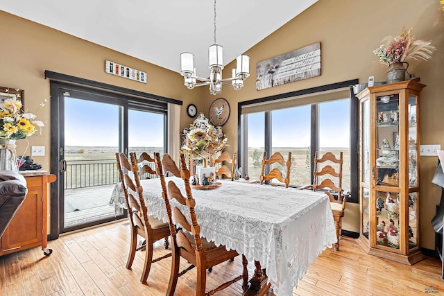 dining room with a chandelier, light hardwood / wood-style flooring, and lofted ceiling