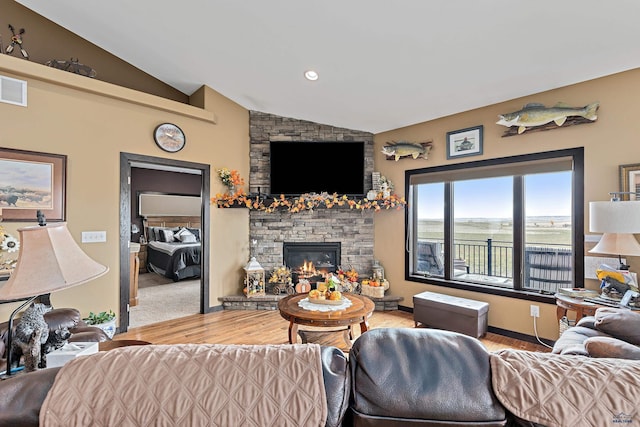 living room featuring wood-type flooring, a stone fireplace, and lofted ceiling